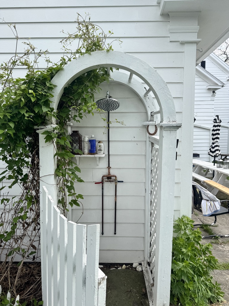 Outdoor shower beneath a white garden arch
