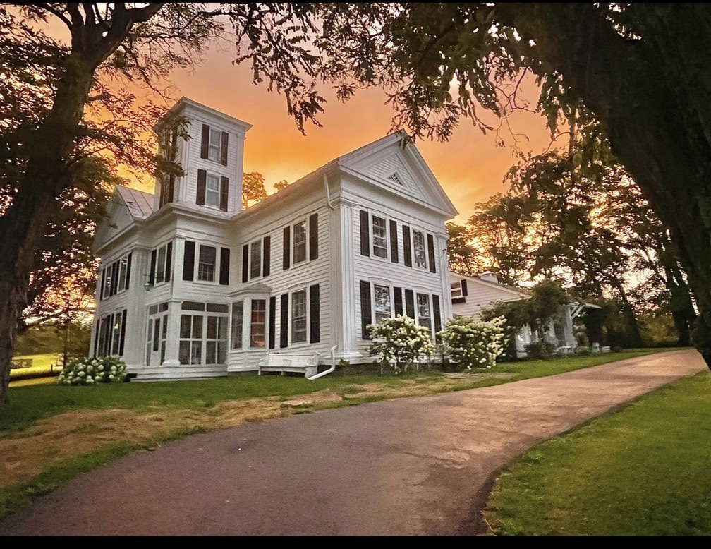 Durham White House framed by trees beneath a brilliant sunset
