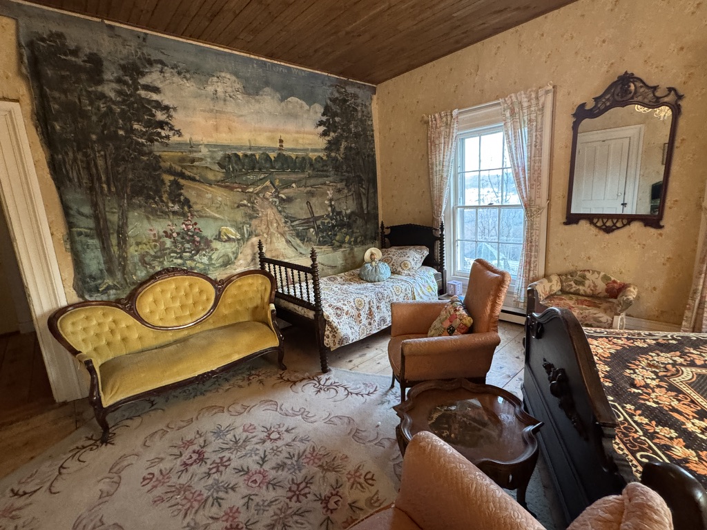 Bedroom sitting area with a landscape mural and yellow settee