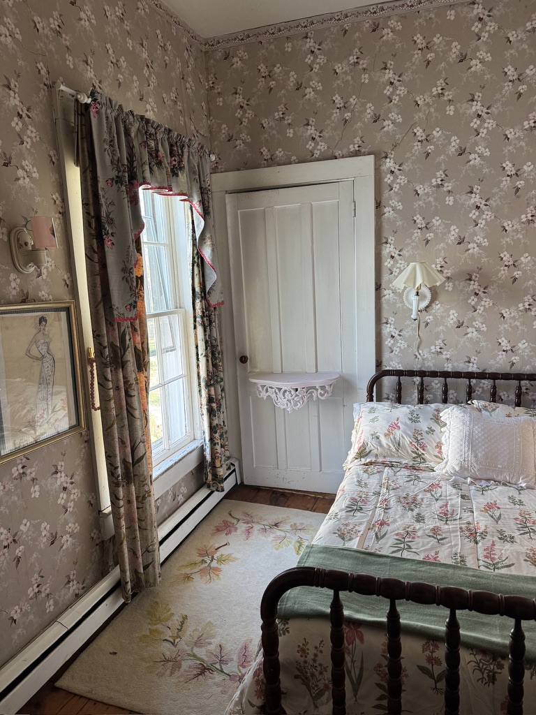 Guest bedroom with an iron bed and floral wallpaper
