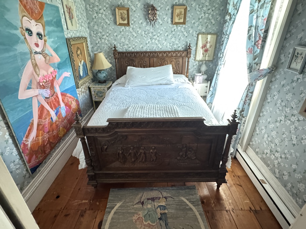 Antique wooden bed beside a painted wall panel