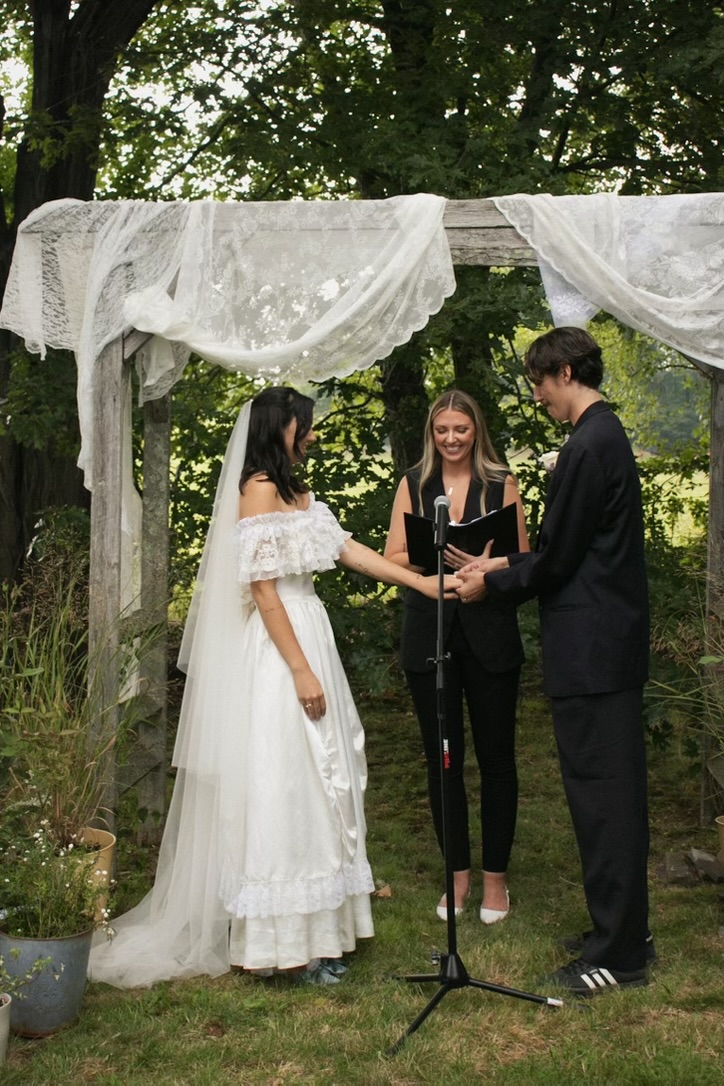 Exchanging vows beneath a white-draped arbor