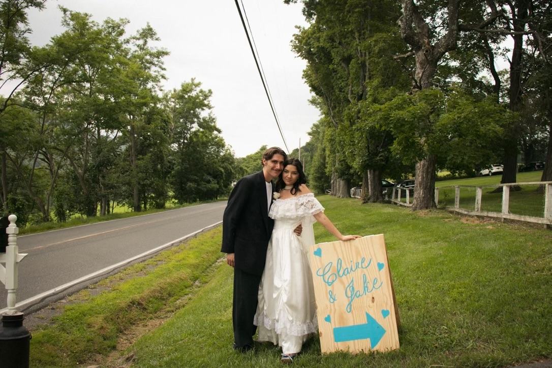 Newlyweds beside a wedding sign on the lawn